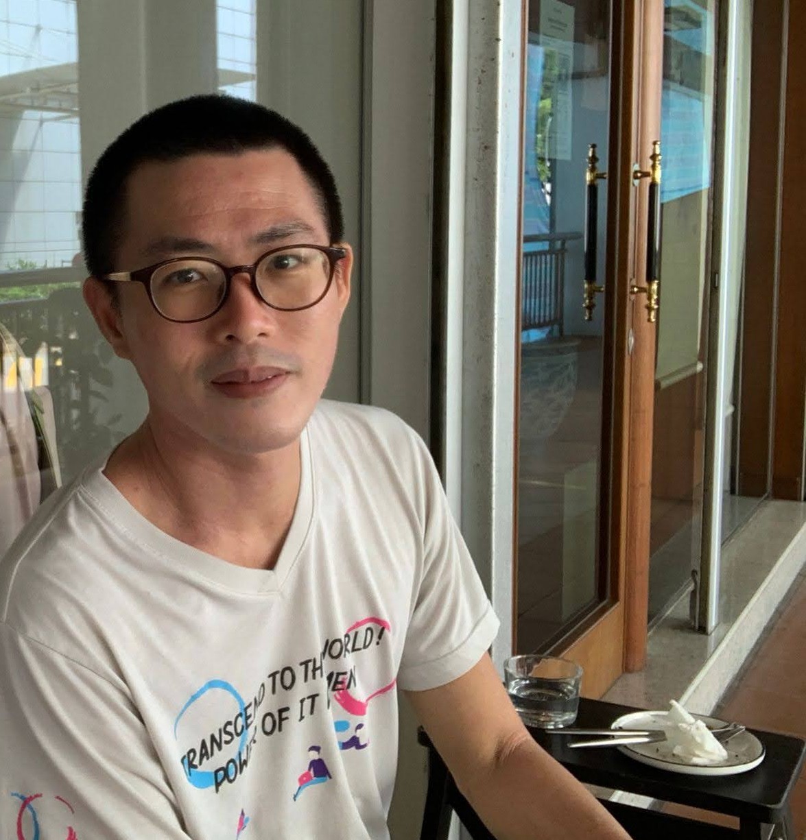 photo of Tony Chen at a cafe/coffee-shop, known as
                                                             Narrative Coffee Stand, on the island of 
                                                             Singapore; circa 2021 A.D. A young man smiles at the camera.